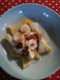 a white plate topped with sliced bananas and other toppings on top of a red table cloth