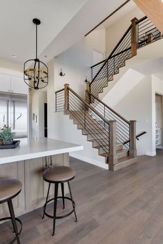 a kitchen with two stools next to a counter and stairs in the middle of it