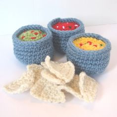 three crocheted bowls with food in them sitting next to each other on a white surface