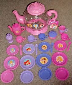 there is a tea set with princess plates, cups and spoons on the floor