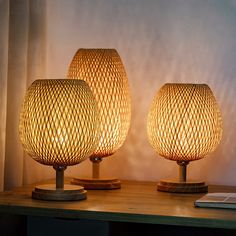 two lamps sitting on top of a wooden table next to a book and lamp shade