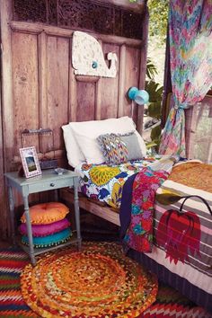 a bed with colorful blankets and pillows on top of it next to a small table