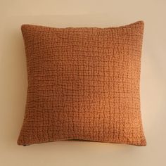 an orange pillow on a white wall