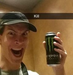 a man holding up a can of monster energy drink in front of his face and mouth