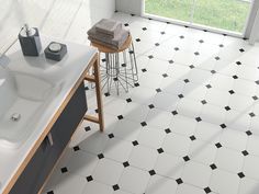 a bathroom with black and white tiles on the floor next to a bathtub, stools and window