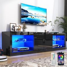 an entertainment center in a living room with blue lights and remotes on the floor