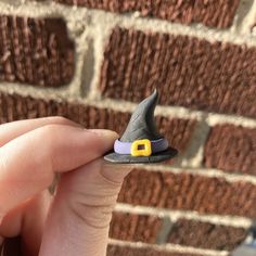 a hand holding a tiny toy witch hat