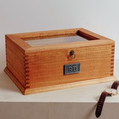 a wooden box sitting on top of a table next to a leather strap and watch