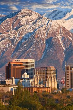 the city is surrounded by mountains and snow capped peaks in the distance, as seen from across the valley