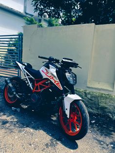 a white and red motorcycle parked in front of a building with a fence behind it