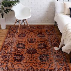 an orange rug in a room with a white chair and potted plant on the floor