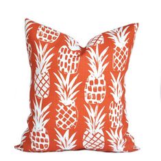 an orange pillow with white pineapples on the front and back, sitting on a white background