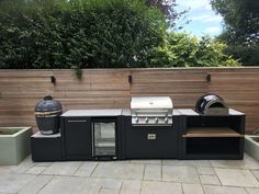 an outdoor bbq with grill, sink and potted plants