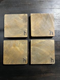 four square wooden coasters with the letter h on them, sitting on a table