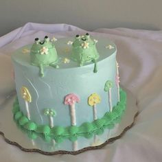 a cake with green frosting and two frogs on top