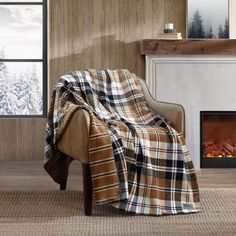 a chair with a blanket on it in front of a fireplace