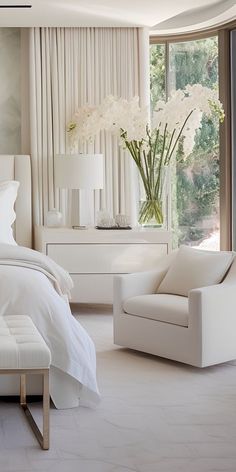 a bedroom with white furniture and large windows