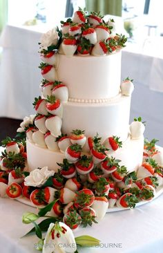 a wedding cake with strawberries and flowers on it