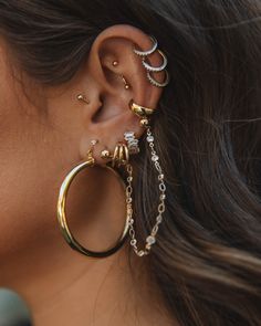 a close up of a person wearing ear rings with chains attached to the back of their ears