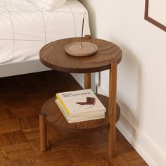 a small wooden table with a book on it next to a white bed and nightstand