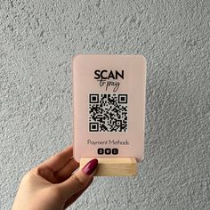 a person holding up a qr code for scan to pay in front of a wall