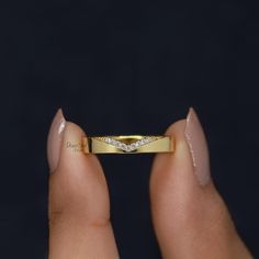 a woman's hand holding a yellow gold ring with three diamonds on it,