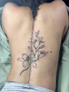 the back of a woman's lower back tattoo with flowers and words on it