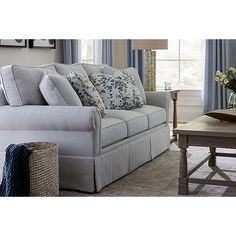 a living room scene with focus on the sofa and chair, coffee table and window