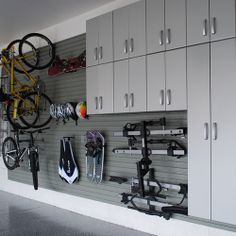 there are many bikes and bicycles on the wall in this bike storage area with white cabinets