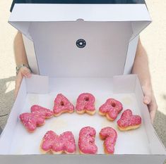 a box filled with pink donuts sitting on top of a table