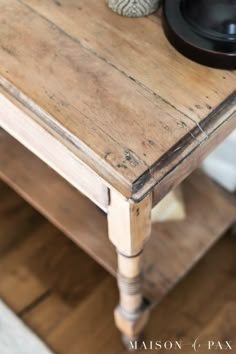 an old wooden table with a black bowl on top