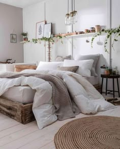 a bed with white linens and pillows in a room next to a mirror, potted plant on the wall