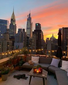 an outdoor living area with couches and tables in front of the cityscape