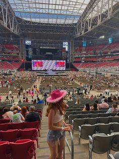 a woman wearing a pink hat standing in front of an empty stadium filled with people