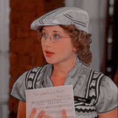 a woman wearing glasses and a hat holding a piece of paper