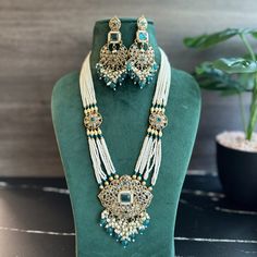 Teal Golden Polki Long Necklace Set. Upgrade your jewelry collection with our Teal Golden Polki Long Necklace Set. Crafted with exquisite teal and gold stones, this set will elevate any outfit. Its long design allows for versatile wear, making it a perfect addition to your wardrobe. Shine bright with this stunning and intricate necklace set. Elegant Turquoise Jewelry With Stone Work, Elegant Turquoise Kundan Necklace, Elegant Turquoise Kundan Necklace For Festive Occasions, Gold Emerald Jewelry Sets For Celebration, Elegant Turquoise Jewelry With Gold Beads, Gold Emerald Necklace With Stone Work, Polki Long Necklace, Intricate Necklace, Teal Necklace