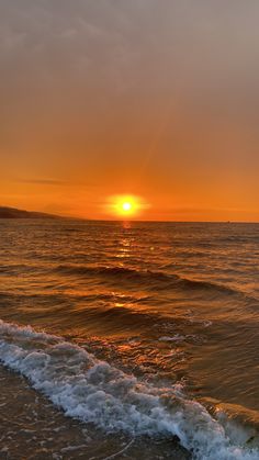 the sun is setting over the ocean with waves