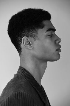 a black and white photo of a young man with an afro hairstyle looking off to the side