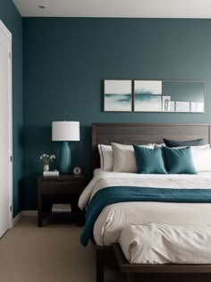 a bedroom with teal walls and white bedding in the center, along with two framed pictures on the wall