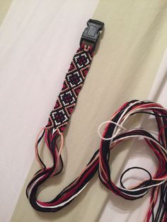 an apple watch strap with red, black and white braiding on it's side