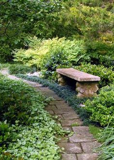 a stone bench sitting in the middle of a garden