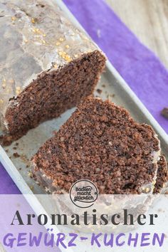 a loaf of chocolate cake sitting on top of a white plate next to a purple napkin