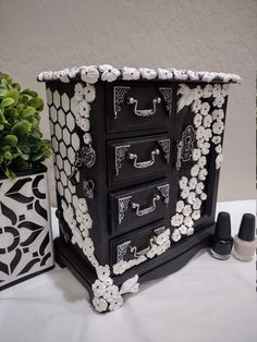 a black and white dresser with flowers painted on the drawers, next to other decorative items