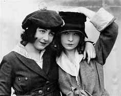 two women in hats are posing for a photo together, one is wearing a coat and the other has a hat on her head