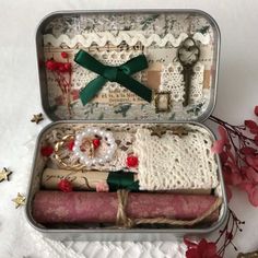 two tins filled with different items sitting on top of a white cloth covered table