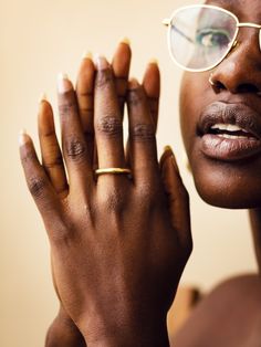 a woman wearing glasses holding her hand up to her face