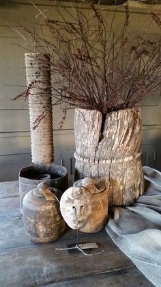 two vases with branches in them sitting on a table next to other pots and containers