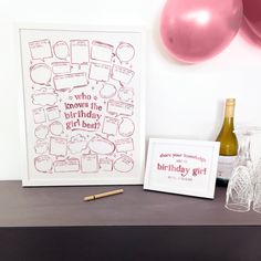 there is a birthday card and wine glass on the table next to it, with balloons in the background