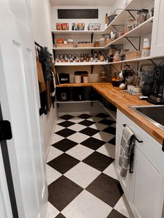 a kitchen with black and white checkered flooring next to open shelving units