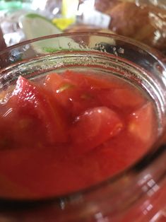 a jar filled with sliced tomatoes on top of a table